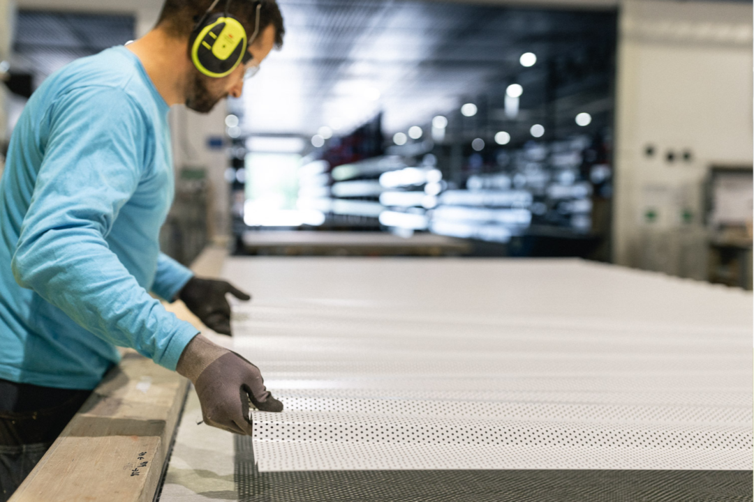 Produksjonsmedarbeider legger på perforterte plater på et takelement